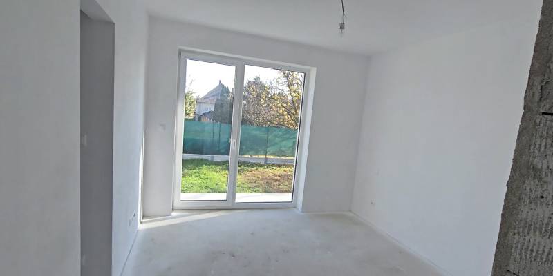 Fehér szoba nagy ablakkal és kilátással a kertre egy családi házban.