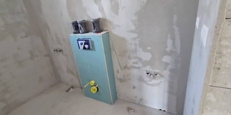 Családi ház befejezetlen fürdőszobája, falba előkészített szereléssel.