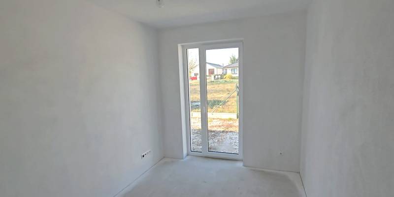 Fehér szoba egy családi házban nagy ablakkal és kilátással a kertre.