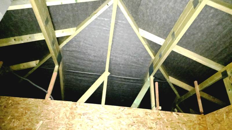 Családi ház fa tetőszerkezettel és OSB lapokkal a tetőtérben.