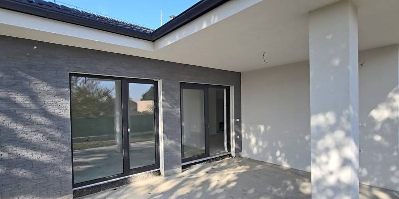 A pihenőterasz egy családi házban Pöstyénben nagy üvegajtókkal és szürke falakkal.