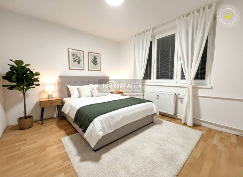 Világos hálószoba egy kétszobás lakásban fa mintázatú padlóval, dekorációval és nagy ablakkal.