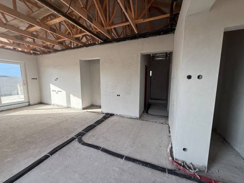 Családi ház belső tere építés alatt álló falakkal és fa dekorációjú padlóval.