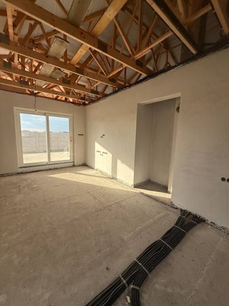 Családi ház belső tere látszó mennyezeti gerendákkal és elektromos szerelés előkészítésével.