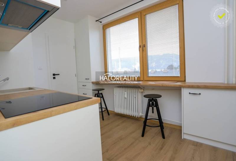 Konyha egy kétszobás lakásban fehér szekrényekkel és fa mintázatú padlóval.