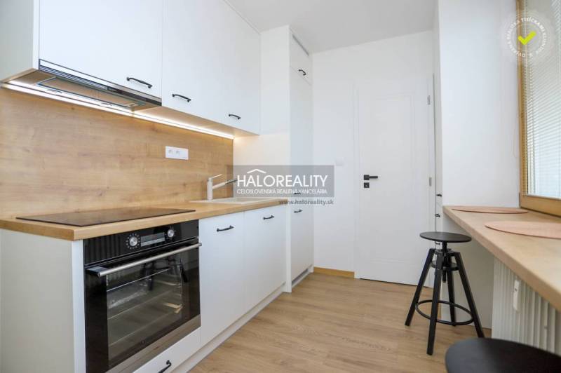 Két szobás lakás konyhája, fa mintázatú padló, világos helyiség nagy ablakkal.