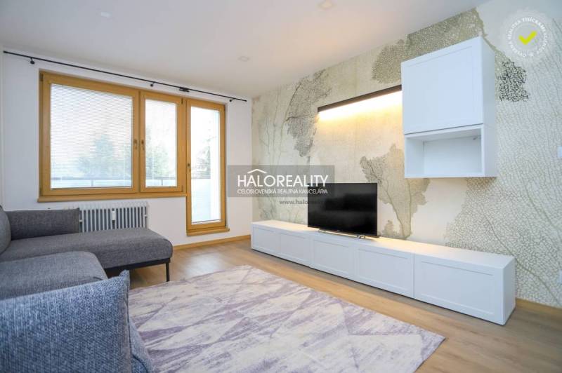 Világos nappali egy kétszobás lakásban kényelmes kanapéval és fa mintázatú padlóval.