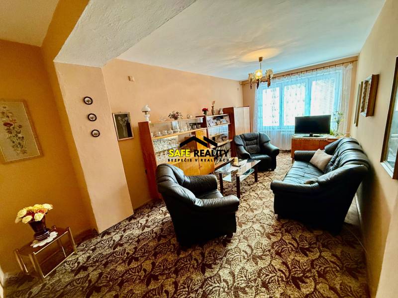 Nappali egy kétszobás lakásban kanapéval és üveges vitrinnel.