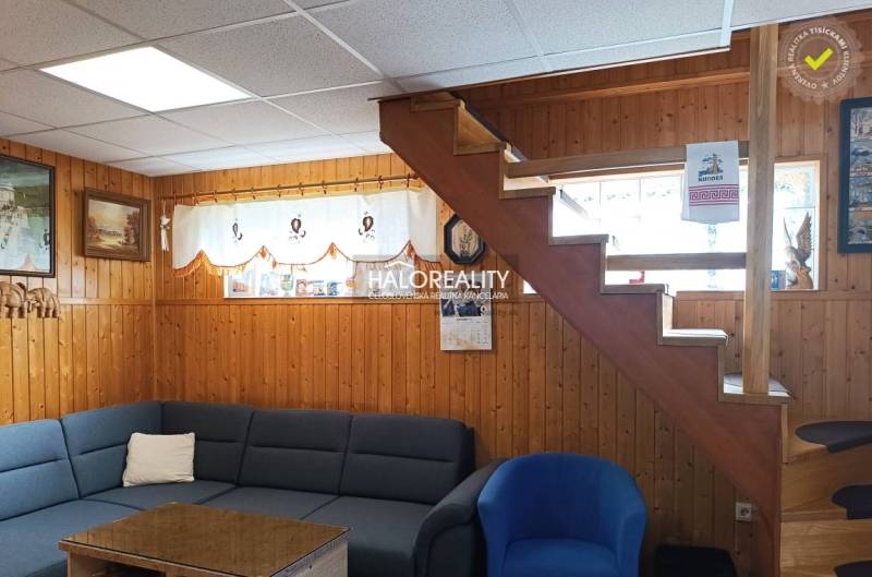 A faház belső tere fa burkolattal, lépcsőkkel, kanapéval és fali dekorációkkal.