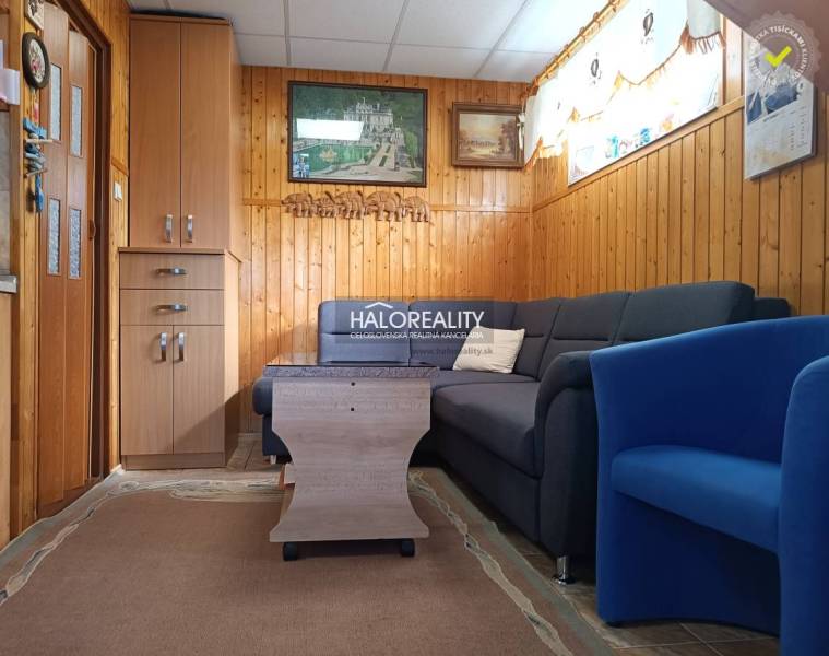 Nappali a házban kanapéval, fotellel és falburkolatokkal.