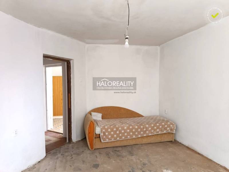 Családi ház belső tere régi kanapéval és nyers betonpadlóval.