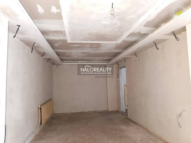 Befejezetlen szoba egy családi házban fehér falakkal és téglapadlóval.