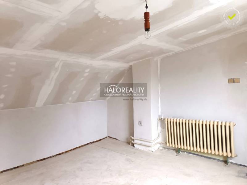 Belső tér fehér mennyezettel, radiátorral és padlóval egy családi házban.