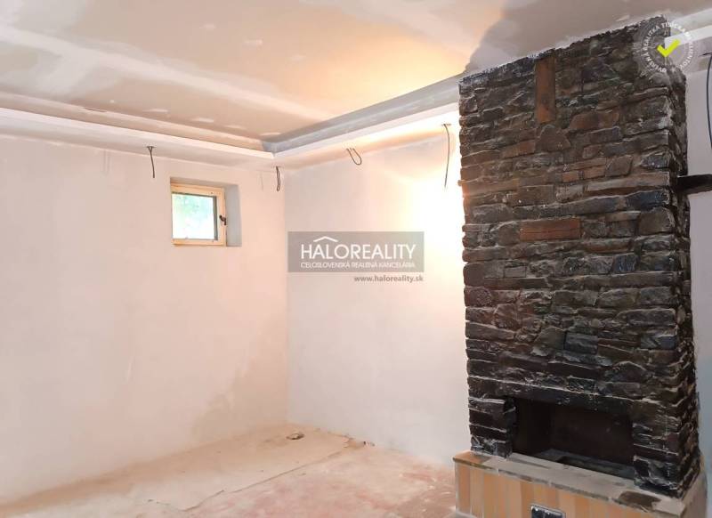 Családi ház belső tere kő kandallóval és kis ablakkal.