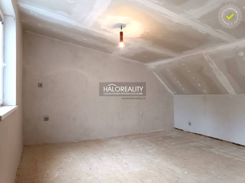 Családi ház be nem rendezett tetőtéri szoba, világos falak és fa padló.