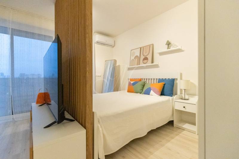 1 szobás lakás ággyal, televízióval és dekoratív párnákkal. Fa dekoros padló.