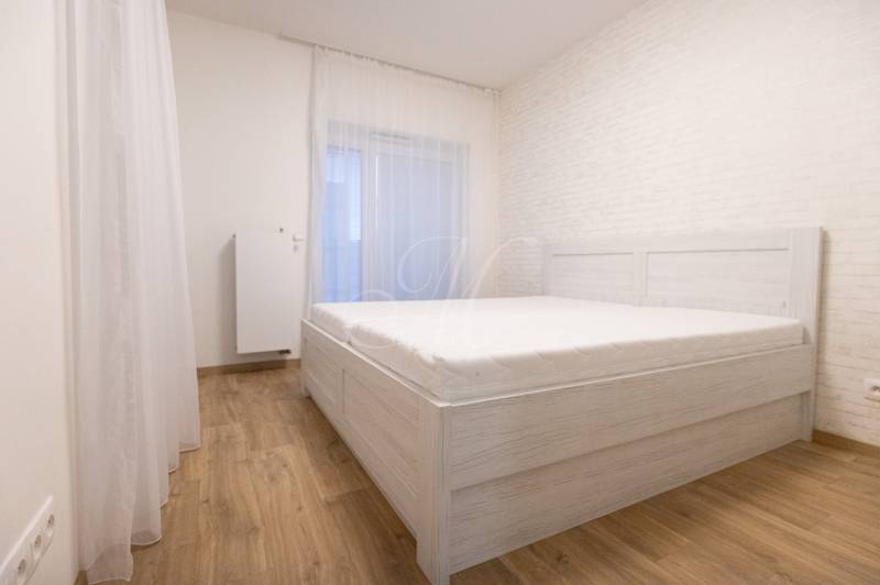 Hálószoba egy kétszobás lakásban, ággyal és fa dekorációjú padlóval.