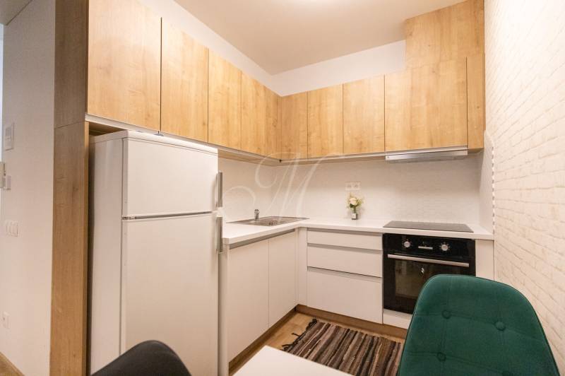 Konyha egy kétszobás lakásban fa dekorációval és fehér szekrényekkel.