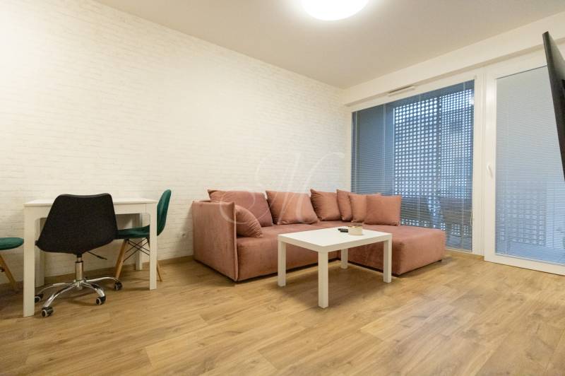 Nappali egy kétszobás lakásban kanapéval, asztallal és fa dekorációjú padlóval.