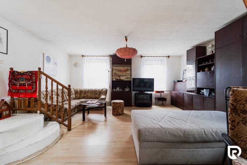 Nappali egy családi házban, fa dekorációjú padlóval és kényelmes ülőgarnitúrával.