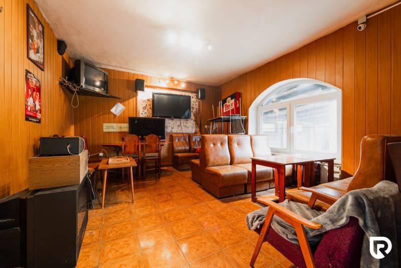 Családi ház belső tere bőr kanapékkal, fa burkolattal és televíziókkal.