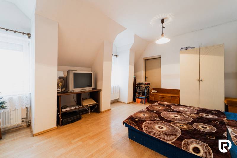 Hálószoba családi házban fa dekor padlóval, régebbi televízióval és tárolóhellyel.