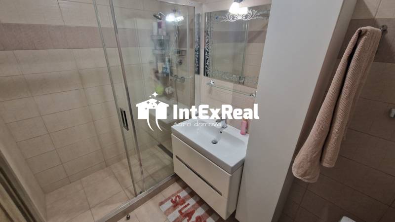 Fürdőszoba csempékkel és zuhanyzóval egy háromszobás lakásban.