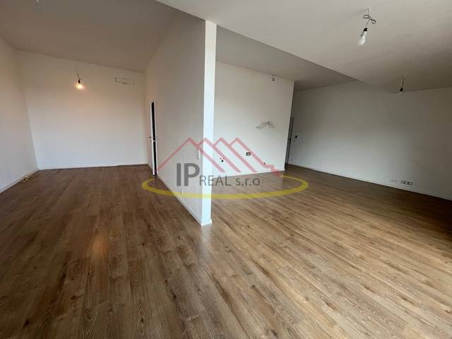 Szoba egy kétszobás lakásban, fa dekoros padlóval és fehér falakkal.