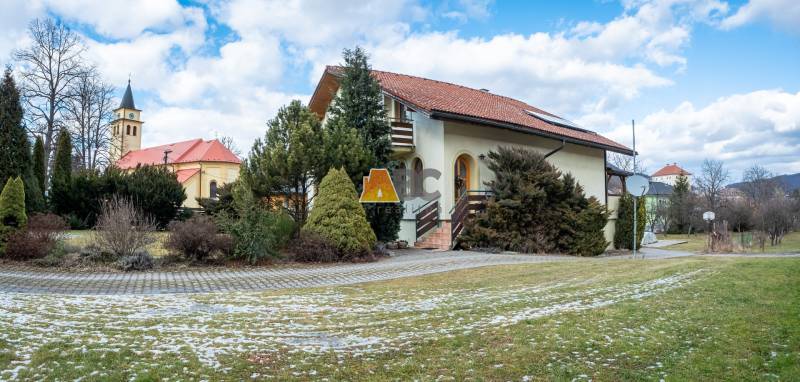 Egy villa az Andreja Sládkoviča utcában Zsarnócán, zölddel körülvéve, háttérben a templommal.