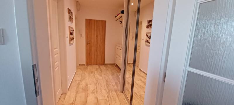 Folyosó egy 3 szobás lakásban fa dekor padlóval és beépített szekrénnyel.