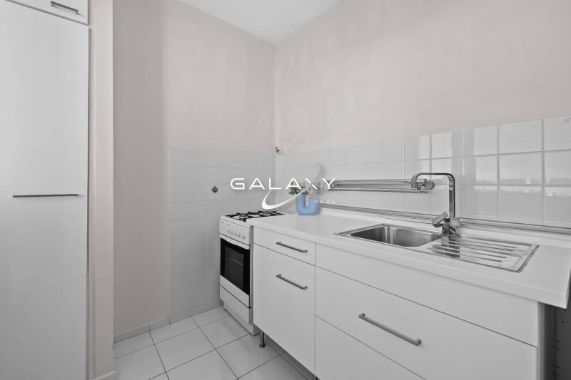 Konyha egy egyszobás lakásban fehér konyhabútorral és tűzhellyel.