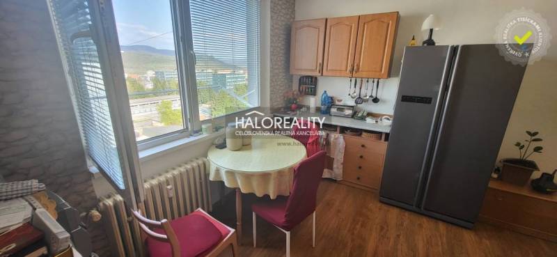 Konyha egy egyszobás lakásban asztallal, székekkel és kilátással az ablakból.