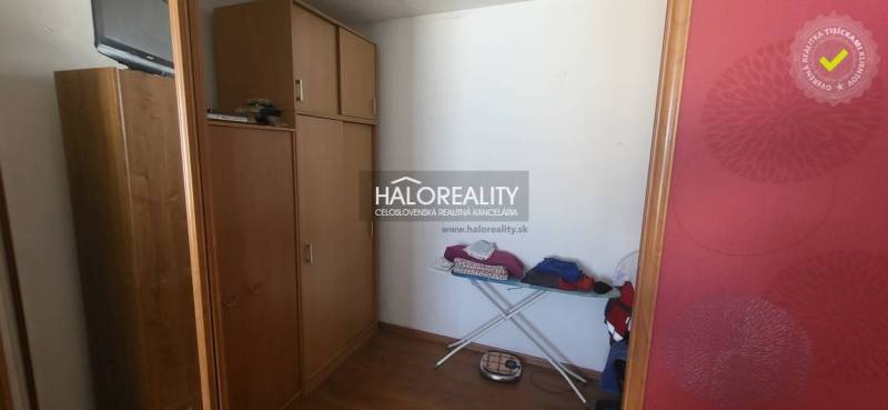 Gardrób egy egyszobás lakásban fa dekorral, tárolószekrények, vasalódeszka.