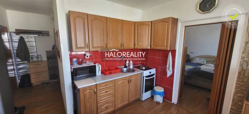 Konyha egy egyszobás lakásban fa szekrényekkel, mikrohullámú sütővel és tűzhellyel.