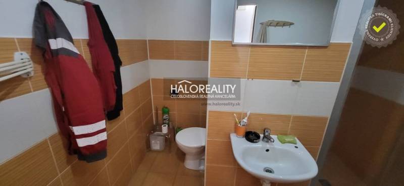 Fürdőszoba WC-vel és mosdóval egy egyszobás lakásban, meleg tónusú csempékkel.