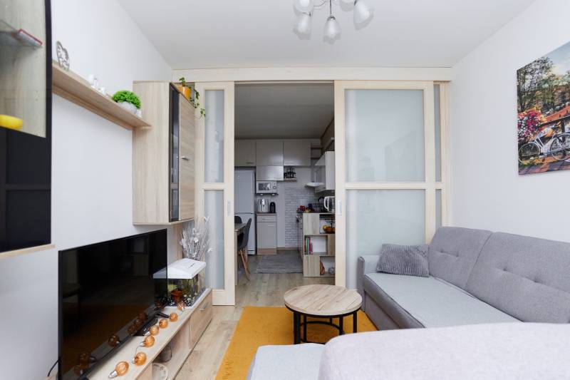 Nappali egy kétszobás lakásban konyhával és fa dekorációjú padlóval.