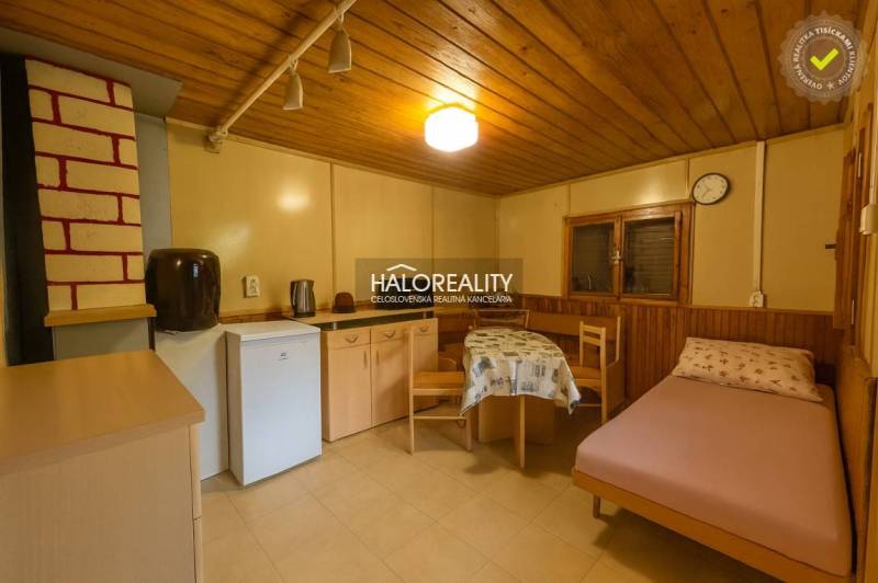 Szoba fa dekorációjú padlóval, egyszerű berendezéssel, ággyal és konyhasarokkal.