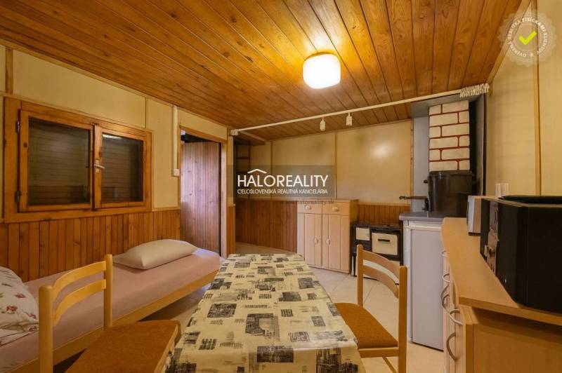 Belső tér asztallal, székekkel és szövet huzatú fotellel, fa dekorációjú padlóval.