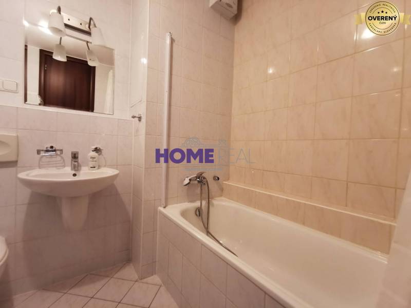 Fürdőszoba egy kétszobás lakásban káddal, mosdóval és tükörrel.