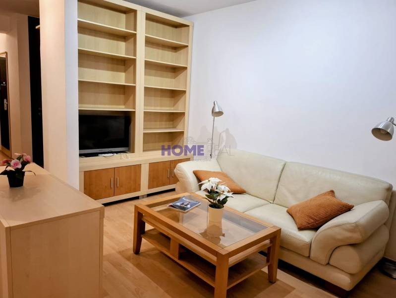 Nappali egy kétszobás lakásban bőrkanapéval és beépített polccal.