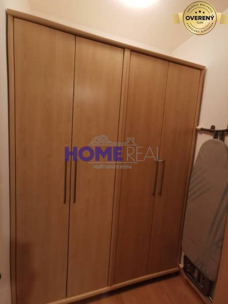 A kétszobás lakásban látható egy fa dekorációjú szekrény és egy vasalódeszka.