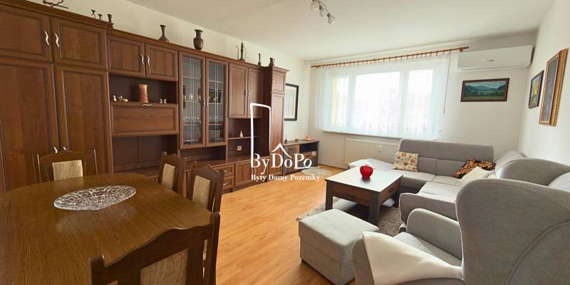 Nappali egy háromszobás lakásban, fa dekoros padlóval és nagy ülőgarnitúrával.