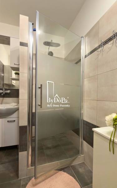 Zuhanyzó modern csempékkel és mosdóval egy háromszobás lakásban.