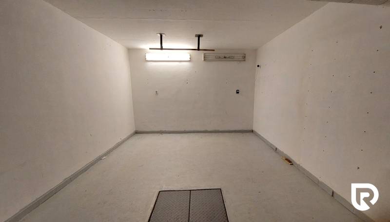 Tágas szoba fehér falakkal és világos megvilágítással egy háromszobás lakásban.