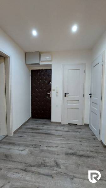 Előszoba egy 3 szobás lakásban, fa dekor padlóval és fehér ajtókkal.