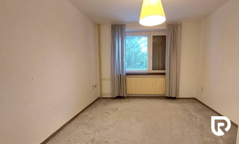 Tágas szoba függönyökkel és szőnyeggel egy háromszobás lakásban.