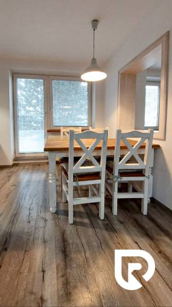 Étkező rész fa dekor padlóval egy 3 szobás lakásban fehér bútorokkal.