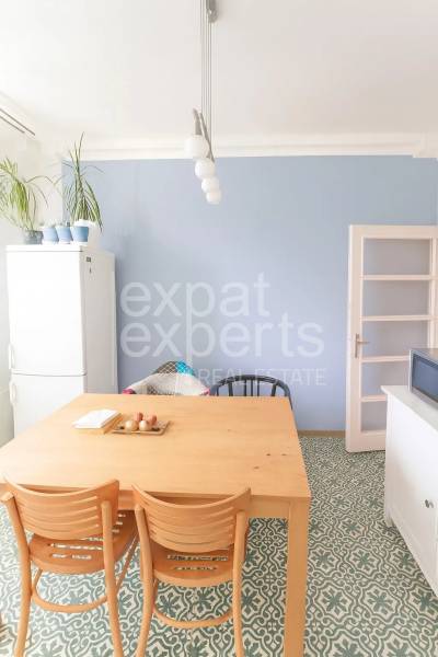 Étkező sarok egy háromszobás lakásban faasztallal és dizájnos padlóval.