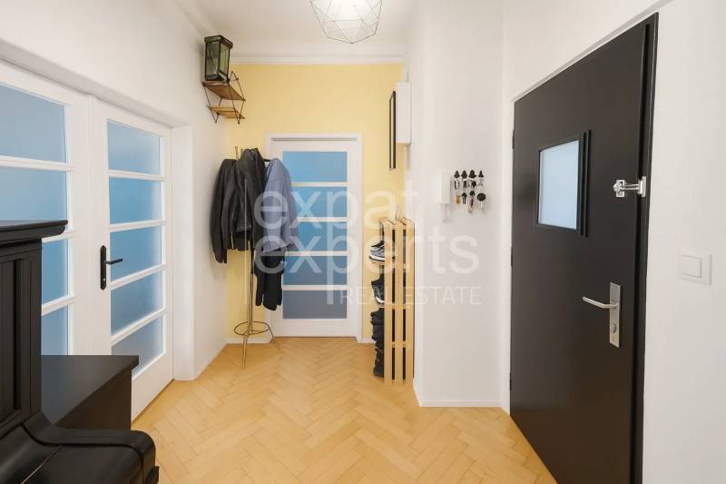 Folyosó egy 3 szobás lakásban, fa dekor padlóval, fogassal és ajtókkal.