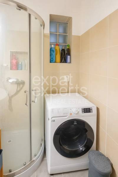 3 szobás lakás fürdőszobája zuhanyzóval és mosógéppel, bézs csempék.